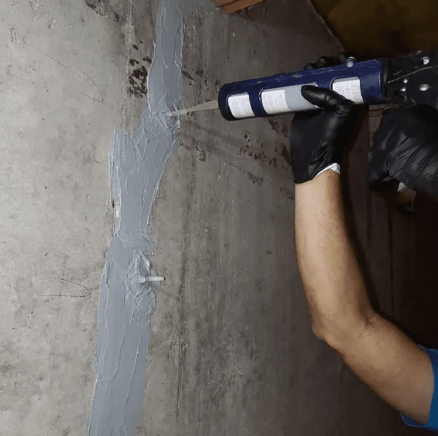 a person using a tube to seal a crack