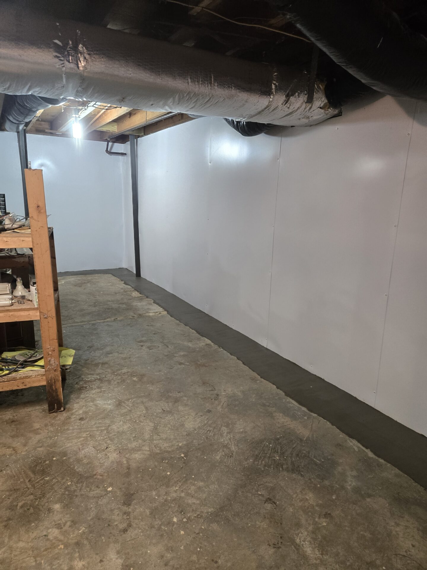 Tilted view of a basement with exposed ductwork, unfinished walls